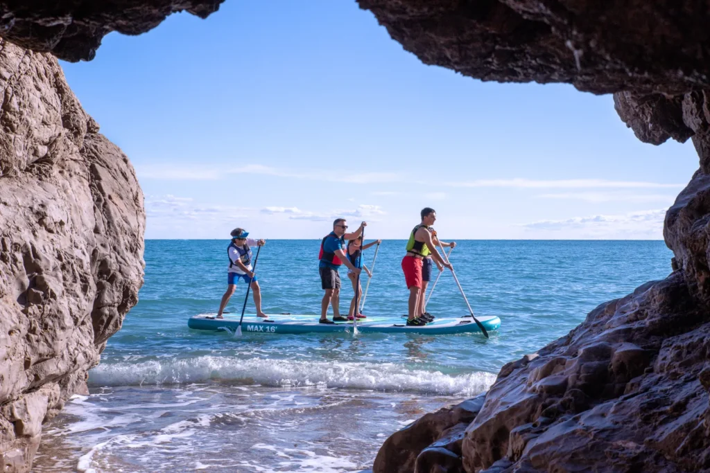 Équipe sur un stand-up paddle géant devant la plage