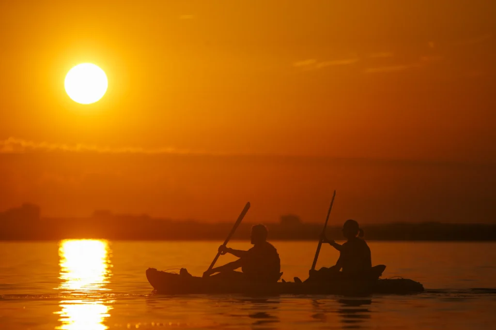 Kayak biplace en ombre chinoise devant le soleil couchant sur l'étang